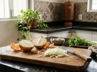 Tábua de madeira com cebola cortada ao meio e fatias, ao lado de uma faca, sob luz de janela